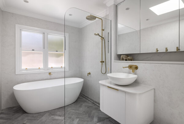 Contemporary bathroom renovation with herringbone floor pattern and gold fixtures in Bellevue Hill