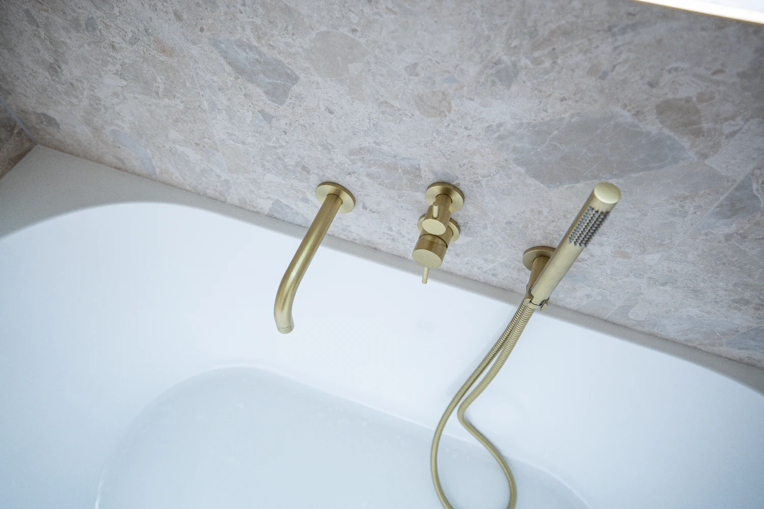 Brushed brass bath mixer and hand-held shower, set into Norrock Ivory.