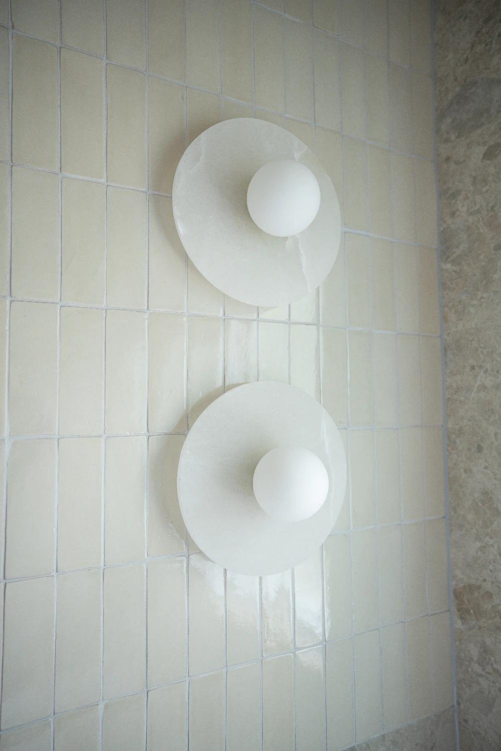 Marble wall sconces on the Zellige Natural feature wall — the glaze catching every flicker of light.
