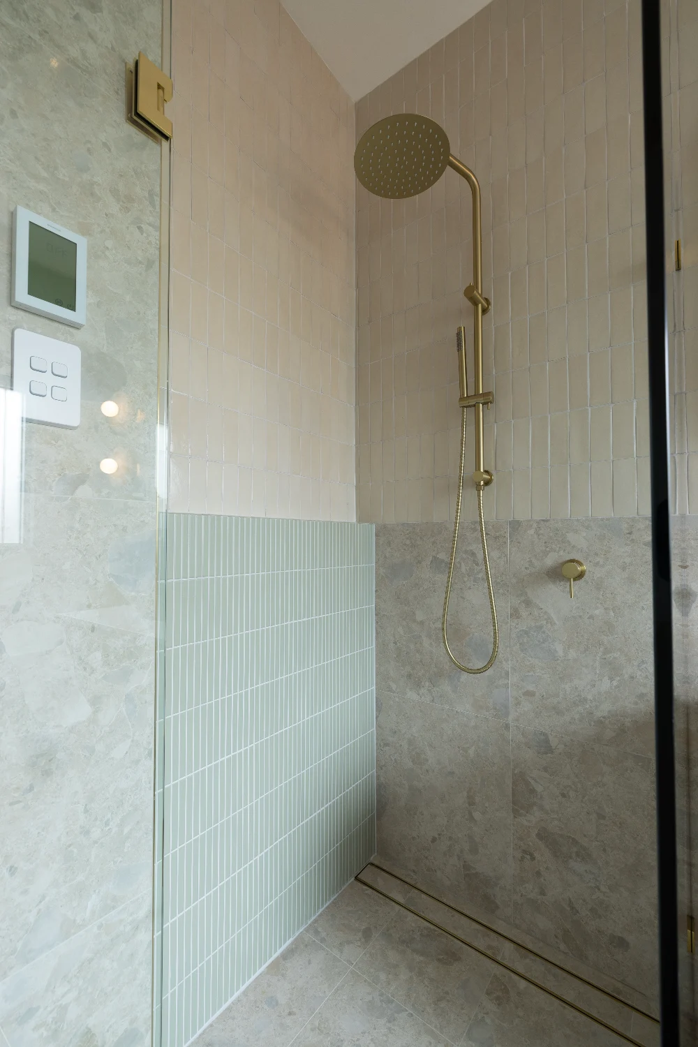 Shower head — brushed brass meeting Kit Kat Sage and Zellige Natural at the corner.