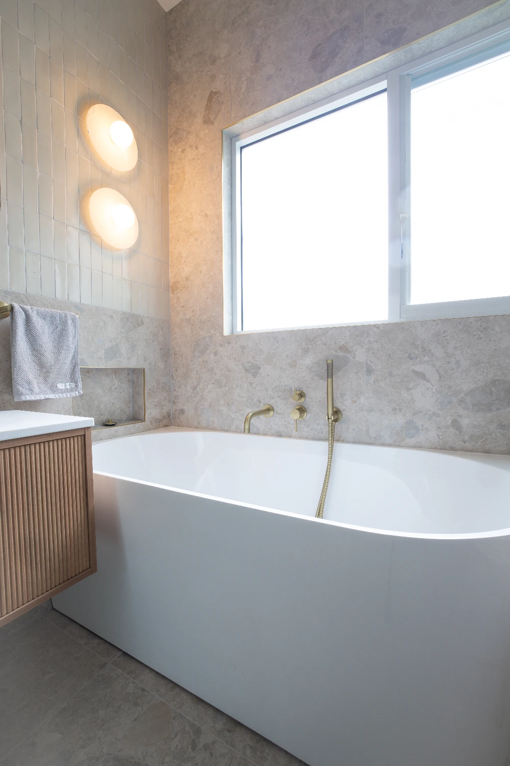 Main bathroom bath — brushed brass tap and hand-held against Norrock Ivory.