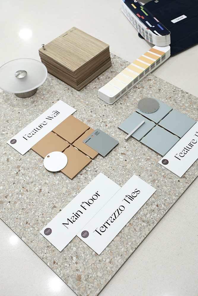 Curated Sydney bathroom tile palette flat-lay with timber samples, colour fan and Design Tiles consultation cards.