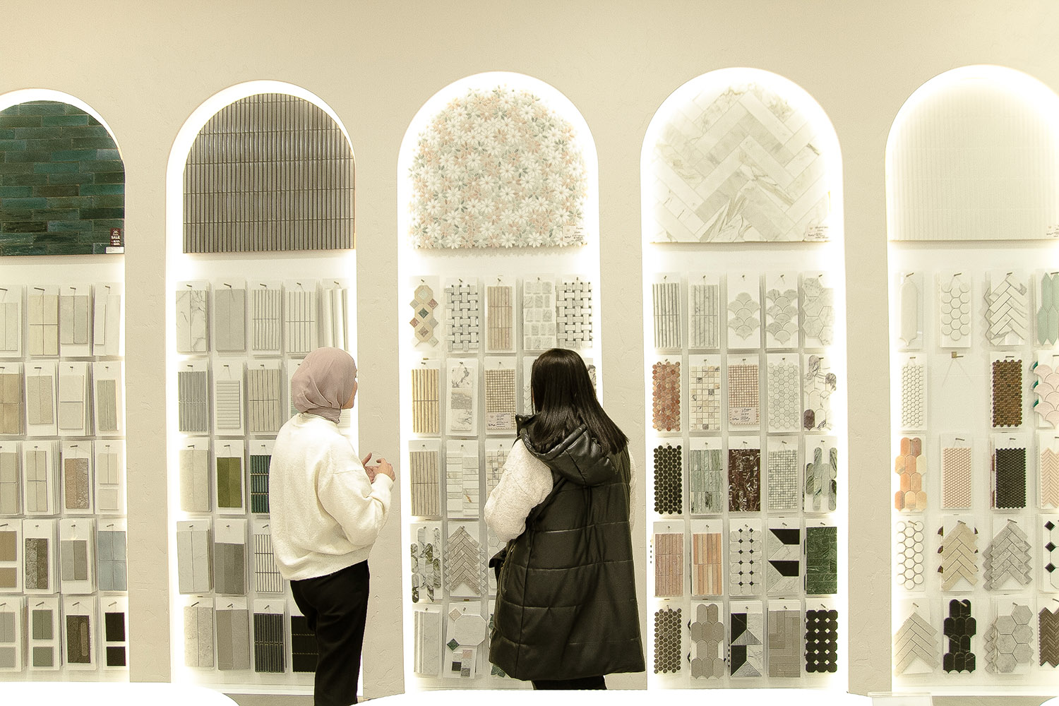 Two people standing at the Design Tiles Rockdale showroom's signature arched sample displays.