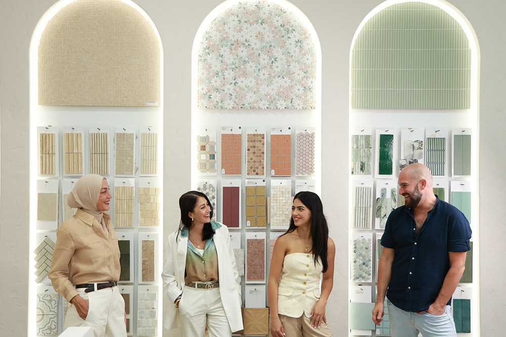The Design Tiles design team standing in front of the Rockdale showroom's signature arched sample displays — backlit niches filled with curated tile paddles, including the green Moroccan handmade zellige range visible in the right arch. The experienced team behind every free in-store zellige consultation, in real showroom light.